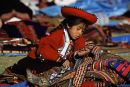 Local Cusco girl at market studying a ruda seed (ruda is used to attract good sales)